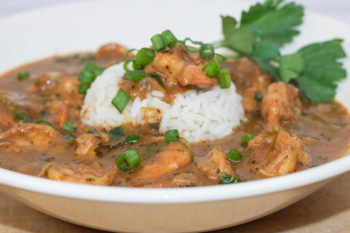 Shrimp Etouffee served with rice and garnish in a white bowl.