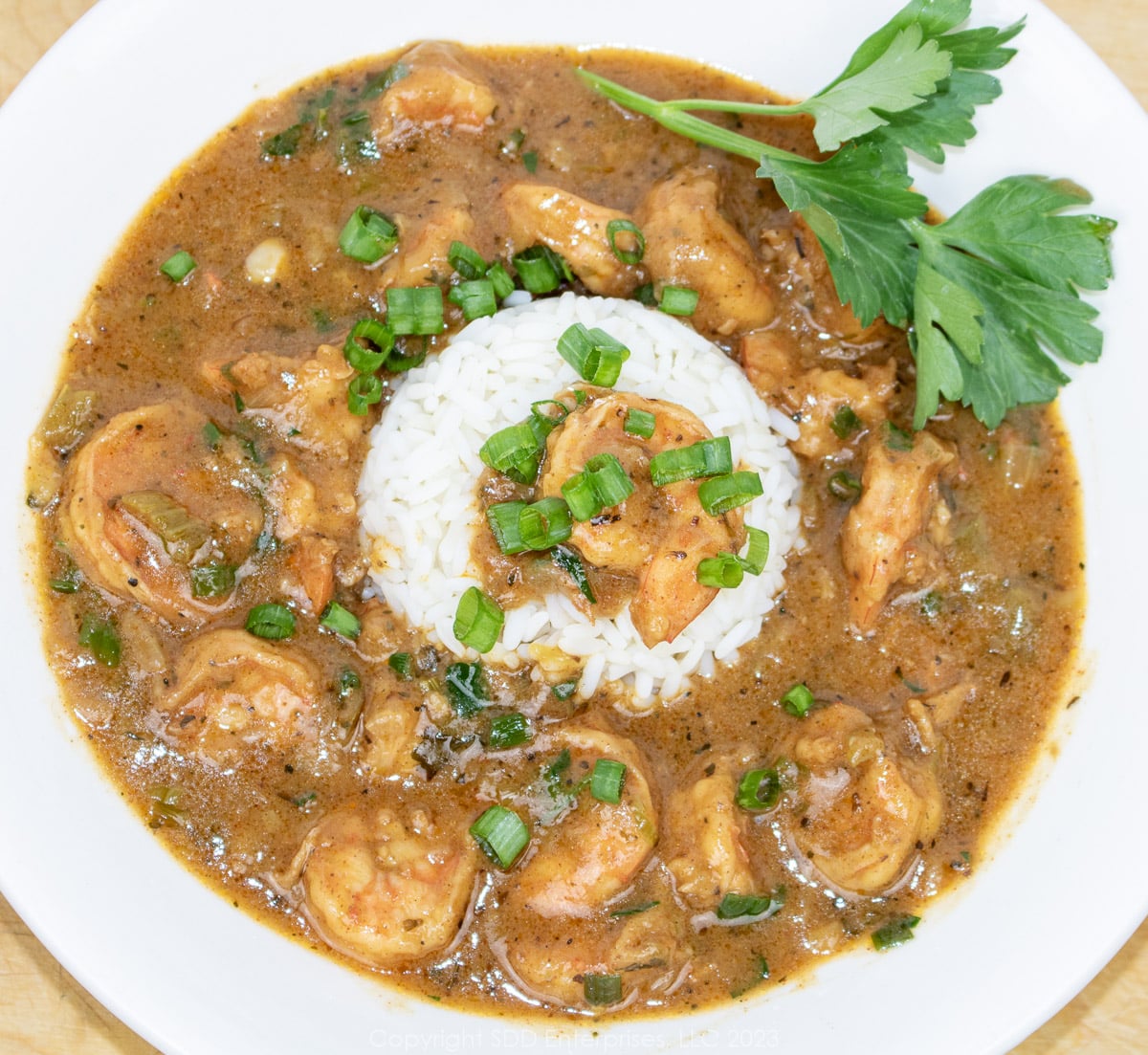 Shrimp Etouffee served with rice and garnish served in a white bowl.
