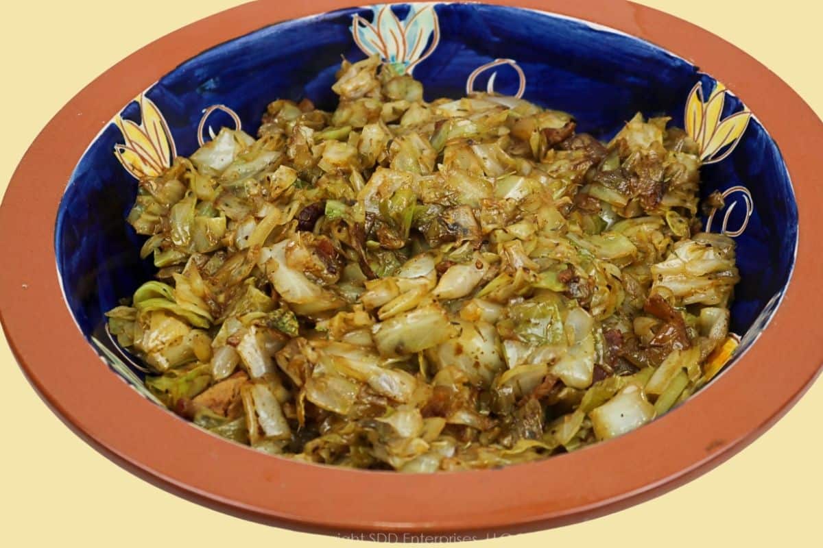 Louisiana-style fried cabbage with bacon served in a blue ceramic bowl.