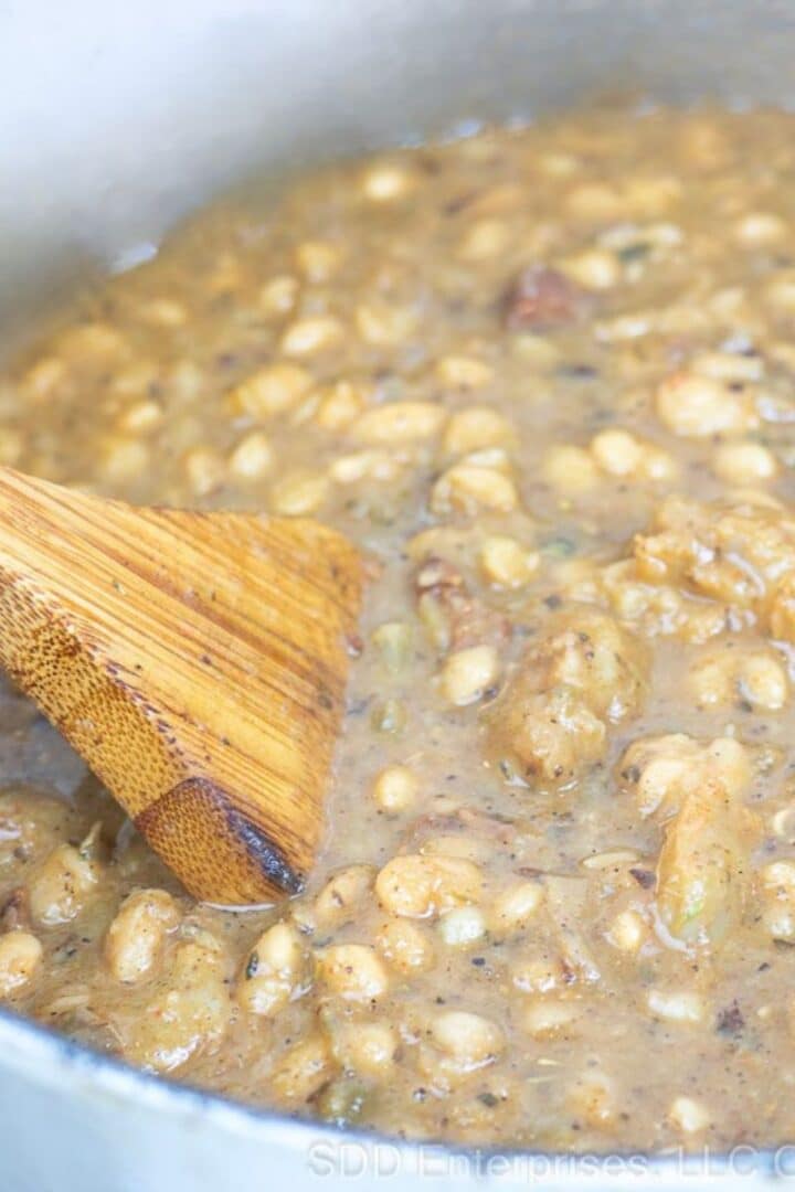 White Beans and Shrimp being stirred in a Dutch oven.
