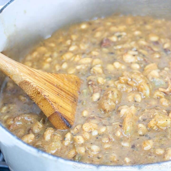 White Beans and Shrimp being stirred in a Dutch oven.