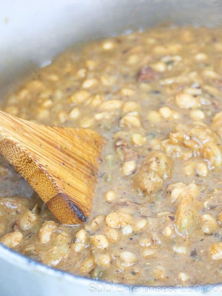 White Beans and Shrimp being stirred in a Dutch oven.