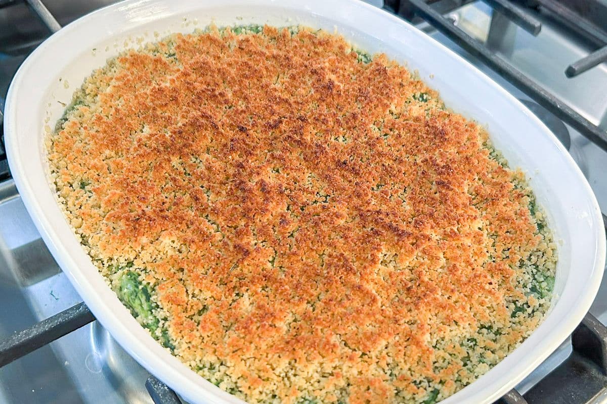 A serving of creamed spinach showing creamy spinach beneath a crisp Romano breadcrumb topping.