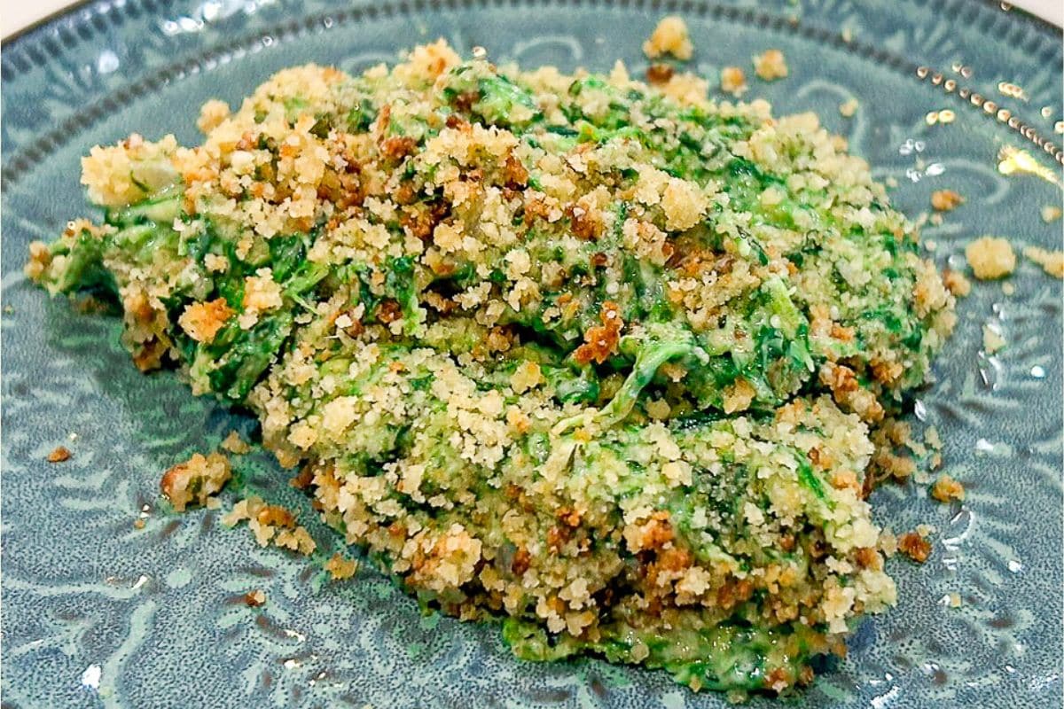 Creamed spinach served from a shallow baking dish with creamy spinach visible beneath the crisp golden topping.